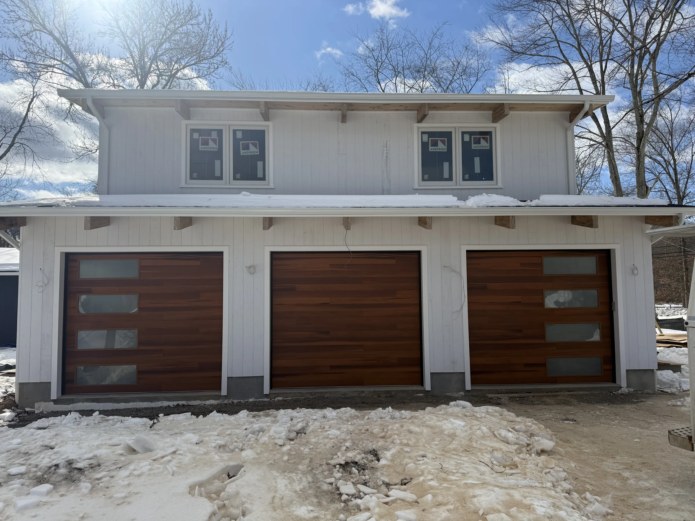 Modern wood-look garage doors with horizontal glass panels installed on a three-car residential garage.
